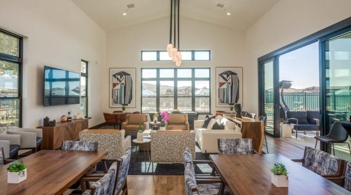 A stylish clubhouse with a dining area, comfortable lounge seating, and large windows offering outdoor views.