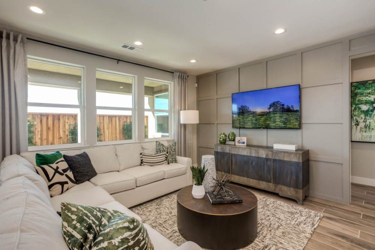 A cozy living room with a large sectional sofa, stylish accent pieces, and a wall-mounted TV, offering a relaxing space with a contemporary design ideal for family gatherings.