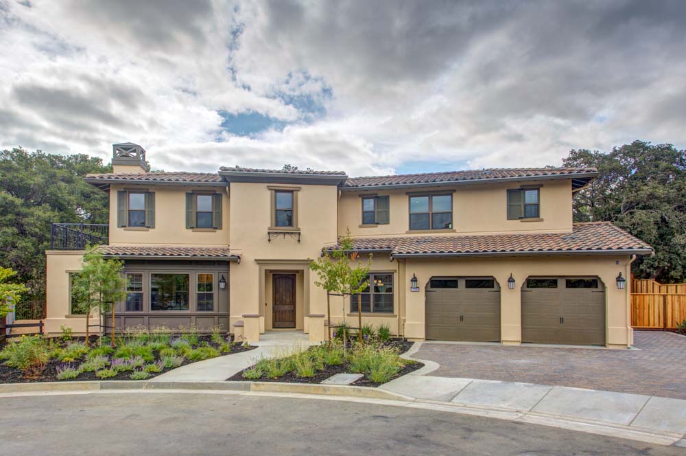 Elegant two-story home with a Mediterranean design featuring beige stucco walls, a tile roof, and a well-manicured front yard, highlighting the architectural beauty and serene residential setting.