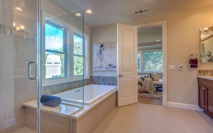 A modern bathroom showcasing a walk-in shower, freestanding tub, and a neutral color palette, complemented by natural light and contemporary art.
