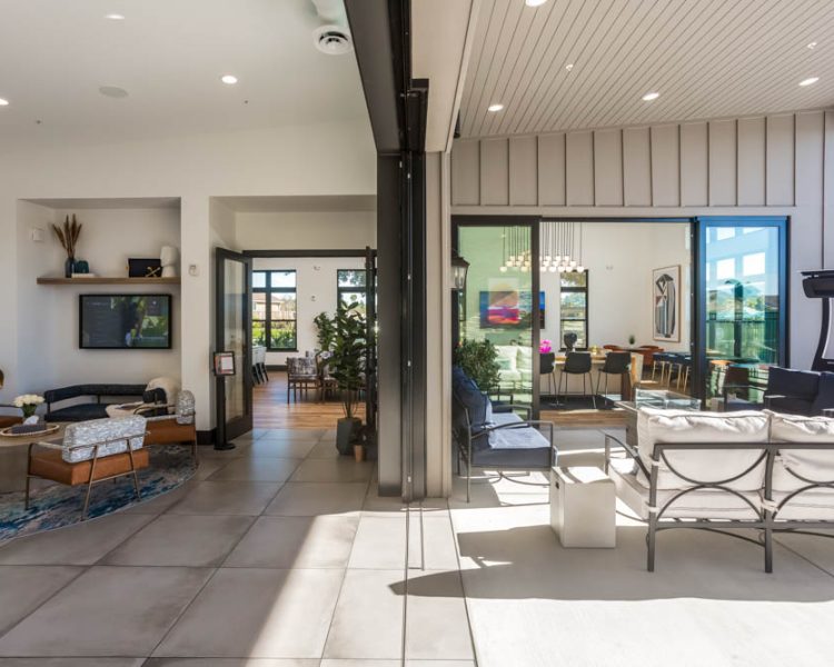 A stylish lounge area featuring contemporary seating, a large open sliding door revealing poolside views, and modern decor for a sophisticated indoor-outdoor living experience.
